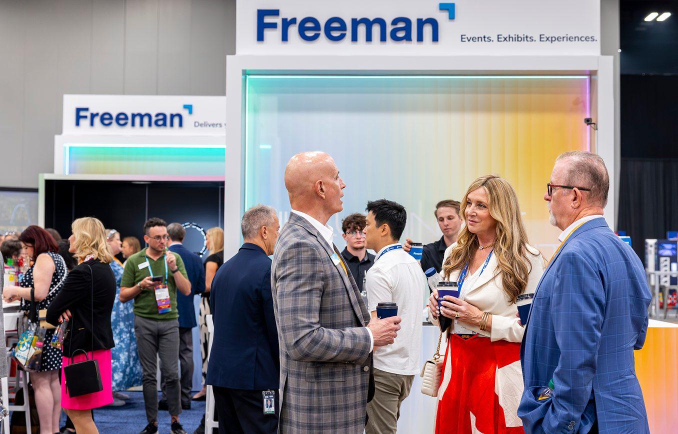 Attendees networking at a Freeman trade show booth